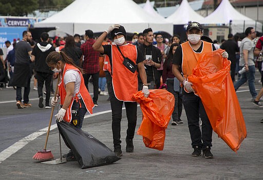 Workers wear protective masks as a precaution against the spread of the new coronavirus, at the Vive Latino Music Festival, in Mexico City, Saturday, March 14, 2020. On Friday afternoon organizers confirmed that the 21st edition of the festival will go on as planned. However, preventive measures will be taken, such as checking the temperature of the attendees upon admission and providing antibacterial gel. (AP Photo/Christian Palma)