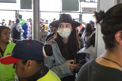 A music fan wears a protective mask as a precaution against the spread of the new coronavirus, as enters the venue for the Vive Latino Music Festival, in Mexico City, Saturday, March 14, 2020. On Friday afternoon organizers confirmed that the 21st edition of the festival will go on as planned. However, preventive measures will be taken, such as checking the temperature of the attendees upon admission and providing antibacterial gel. (AP Photo/Christian Palma)