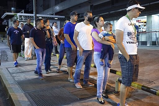 People line up outside a supermarket after President Nicol&aacute;s Maduro ordered residents in the capital of Caracas and six states to stay home under a quarantine in a bid to control the spread of the coronavirus in Caracas, Venezuela, Sunday, March 15, 2020. (AP Photo/Ariana Cubillos)