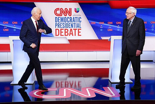 Former Vice President Joe Biden, left, extends his elbow to greet Sen. Bernie Sanders, I-Vt., right, as they participate in a Democratic presidential primary debate at CNN Studios in Washington, Sunday, March 15, 2020. (AP Photo/Evan Vucci)