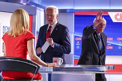 Former Vice President Joe Biden, center, stops to talk with CNN anchor Dana Bash, left, as Sen. Bernie Sanders, I-Vt., right, waves after they participated in a Democratic presidential primary debate at CNN Studios in Washington, Sunday, March 15, 2020. (AP Photo/Evan Vucci)