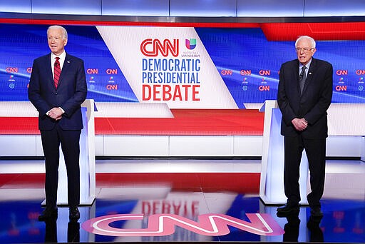 Former Vice President Joe Biden, left, and Sen. Bernie Sanders, I-Vt., right, wait on stage to participate in a Democratic presidential primary debate at CNN Studios in Washington, Sunday, March 15, 2020. (AP Photo/Evan Vucci)