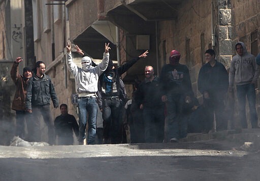 FILE - In this March 23, 2011 file photo, anti-Syrian government protesters flash Victory signs as they protest in the southern city of Daraa, Syria. In a world gripped by a pandemic, global unrest and a fast-moving news cycle, it can be difficult to remember that the war in Syria is still happening. (AP Photo/Hussein Malla, File)