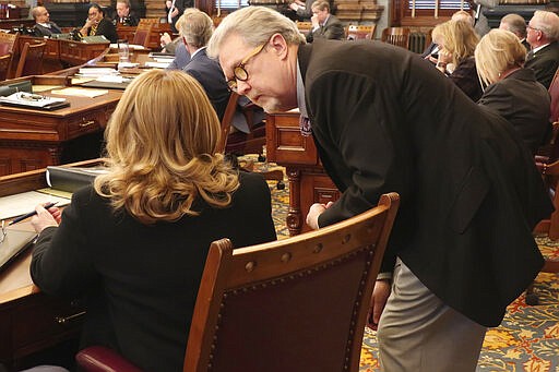 Kansas state Sen. Eric Rucker, R-Topeka, confers with Sen. Caryn Tyson, R-Parker, after the Senate's approval of a bill to launch a new program for highway and bridge improvements, Monday, March 16, 2020 at the Statehouse in Topeka, Kan. Lawmakers are trying to pass a transportation bill and approve a budget to keep state government operating after June before taking an early and long spring break because of the coronavirus pandemic. (AP Photo/John Hanna)