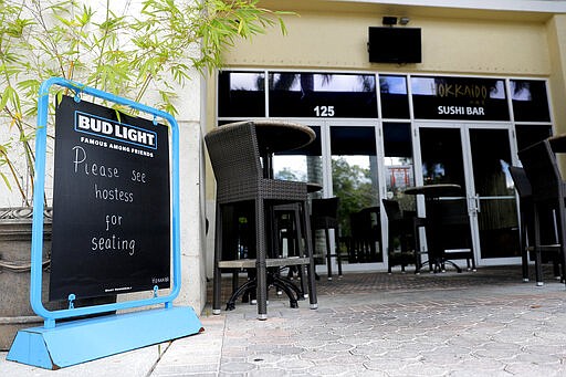 A sign is placed at a deserted at Hokkaido sushi bar, Monday, March 16, 2020, in Jupiter, Fla. The restaurant, which is across the street from Roger Dean Chevrolet Stadium, the spring training baseball home of the St. Louis Cardinals and the Miami Marlins, is normally full with customers on game day. On Sunday night, the Centers for Disease Control and Prevention recommended gatherings of 50 people or more be canceled or postponed across the country for the next eight weeks. Major League Baseball planned to update teams Monday on its health policy. (AP Photo/Julio Cortez)