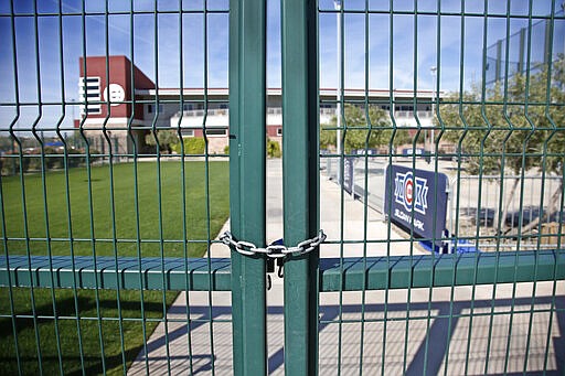 A gate at the Chicago Cubs practice facility at Sloan Park in Mesa, Ariz., is closed and locked Monday, March 16, 2020. The remainder of spring training baseball games have been canceled due to the coronavirus. (AP Photo/Sue Ogrocki)