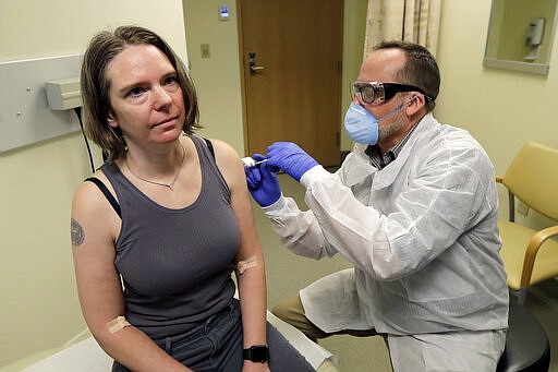 A pharmacist gives Jennifer Haller, left, the first shot in the first-stage safety study clinical trial of a potential vaccine for COVID-19, the disease caused by the new coronavirus, Monday, March 16, 2020, at the Kaiser Permanente Washington Health Research Institute in Seattle. (AP Photo/Ted S. Warren)