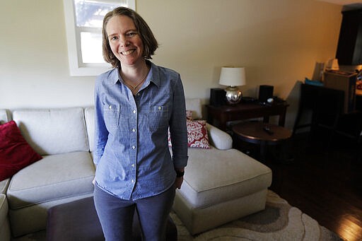 Jennifer Haller poses for a photo in the living room of her home, Monday, March 16, 2020, in Seattle. Earlier in the day, Haller was the first person to receive a shot of a potential vaccine for COVID-19, the disease caused by the new coronavirus, at the start of the first-stage safety study clinical trial of the vaccine at the Kaiser Permanente Washington Health Research Institute in Seattle. (AP Photo/Ted S. Warren)