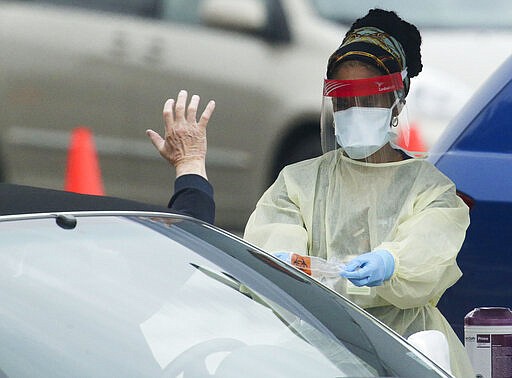 DCH Regional Medical Center opened a drive through testing facility for the Covid-19 virus Monday, March 16, 2020, in Tuscaloosa, Alabama. Tuscaloosa had three confirmed cases of Covid-19 as of Monday morning. A person who has given a saliva sample drops the cup containing his saliva into a bag which the nurse will seal up and forward for testing. (Gary Cosby Jr./The Tuscaloosa News via AP)