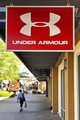 A shopper walks past a closed Under Armor store Monday, March 15, 2020, in Phoenix. Under Armour on Sunday evening announced it will close all 188 of its company stores in North America from March 16 through March 28 as a precaution amid the global spread of coronavirus. According to the World  Health Organization, most people recover in about two to six weeks, depending on the severity of the illness.  (AP Photo/Matt York)