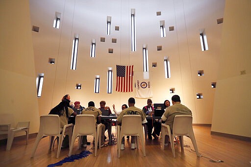 In this Saturday, March 14, 2020 photo Chicago election officials register inmates to vote and participate in early voting for the March 17 primary at a Cook County Jail chapel in Chicago. (AP Photo/Charles Rex Arbogast)