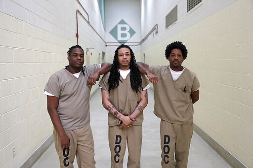 In this Thursday, March 12, 2020, inmates at the Cook County Jail from left, Joshua Cavin, Sean Allen, and Sirjerathan Wilson, pose for a portrait outside cell pod &quot;B&quot; after talking with The Associated Press about participating in early voting for the March 17, Illinois primary at the jail in Chicago. (AP Photo/Charles Rex Arbogast)