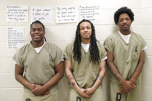 In this Thursday, March 12, 2020, inmates at the Cook County Jail from left, Joshua Cavin, Sean Allen, and Sirjerathan Wilson, pose for a portrait in a jail classroom after talking with The Associated Press about participating in early voting for the March 17, Illinois primary at the jail in Chicago. (AP Photo/Charles Rex Arbogast)