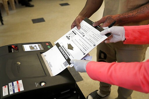 In this Saturday, March 14, 2020 photo, a Cook County jail inmate cast his ballot as he participates in early voting for the March 17, Illinois primary at the jail in Chicago. (AP Photo/Charles Rex Arbogast)