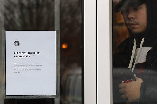 A sign informs customers that the business is open for takeout only to help stop the transmission of the new coronavirus at a Starbucks in Northbrook, Ill., Monday, March 16, 2020. Starbucks announced Sunday its company-owned stores across the U.S. and Canada will shift to a &quot;to go&quot; model for at least two weeks to encourage social distancing. While customers can still walk up to the counter and order, there will be no seating in stores. (AP Photo/Nam Y. Huh)