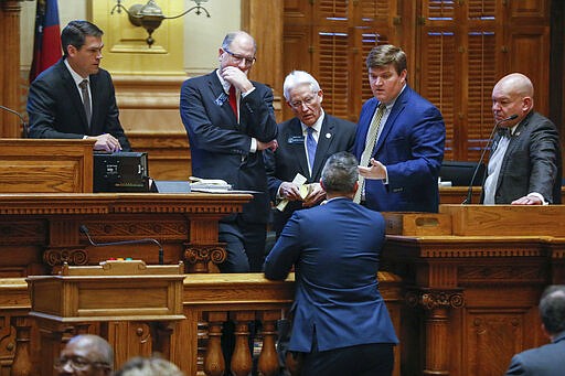 Senate members and staff confer before voting on a resolution granting Gov. Brian Kemp broad powers to combat the spread of the new coronavirus in Georgia, Monday, March 16, 2020, in Atlanta. (Bob Andres/Atlanta Journal-Constitution via AP)