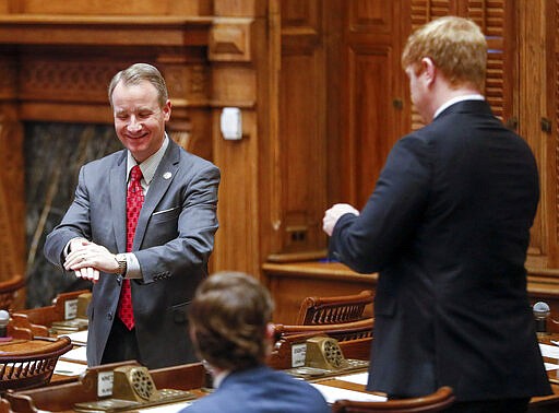 Sen. John Albers, R - Roswell, left, applies hand sanitizer before a session where Georgia lawmakers granted Gov. Brian Kemp broad powers to combat the spread of the new coronavirus in the state, Monday, March 16, 2020, in Atlanta. (Bob Andres/Atlanta Journal-Constitution via AP)