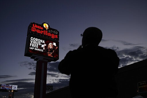 A man looks at a sign at a strip club advertising &quot;coronavirus-free lap dances&quot; March 13, 2020, in Las Vegas. (AP Photo/John Locher)