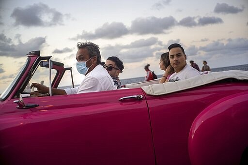 A taxi driver, wearing a protective mask as a precaution against the spread of the new coronavirus, drives his American classic car with tourists in Havana, Cuba, March 13, 2020. (AP Photo / Ramon Espinosa)