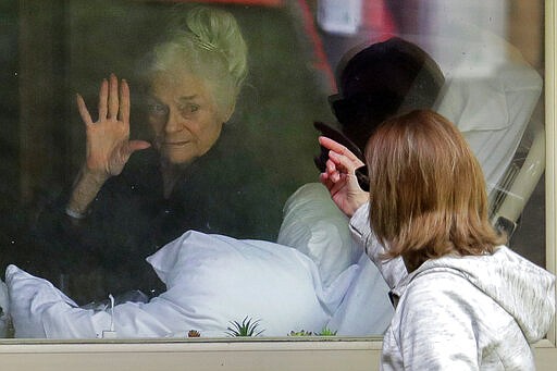 Judie Shape, left, who has tested positive for the coronavirus, waves to her daughter, Lori Spencer, right, March 11, 2020, as they visit on the phone and look at each other through a window at the Life Care Center in Kirkland, Wash., near Seattle. In-person visits are not allowed at the nursing home. The vast majority of people recover from the new coronavirus. According to the World Health Organization, most people recover in about two to six weeks, depending on the severity of the illness. (AP Photo/Ted S. Warren)