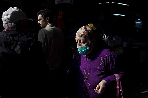 An elderly woman wears a face mask as she shops at a food market in Tel Aviv, Israel, March 15, 2020. (AP Photo/Oded Balilty)