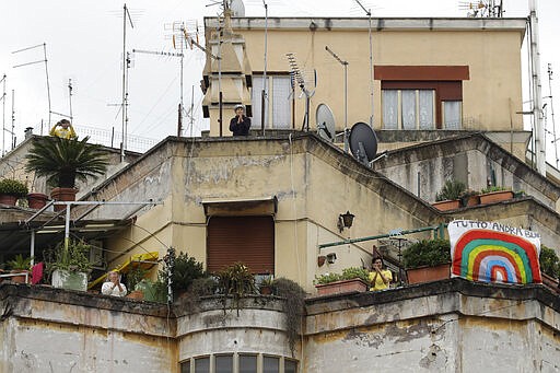 People wave and clap their hands as a banner reading everything will be alright is displayed at right, at the Garbatella neighborhood, in Rome, March 14, 2020. The nationwide lockdown to slow coronavirus is still early days for much of Italy, but Italians are already showing signs of solidarity with flash mob calls circulating on social media for people to ''gather'' on their balconies at certain hours, either to play music or to give each other a round of applause. (AP Photo/Alessandra Tarantino)