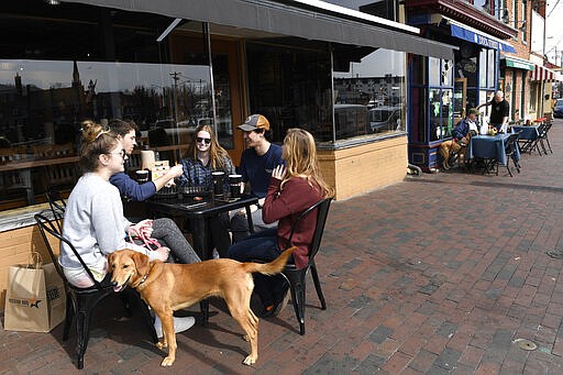 Friends, from left, Erin Carroll of Severna Park, Md., Clay Colehouse of Crownsville, Md., Jessica Goblin of Severna Park, Md., Travis Victorio of Millersville, Md., Mary Fitzell of Millersville, Md., and dog Marty, enjoy lunch during a visit to Annapolis, Monday, March 16, 2020. Maryland Gov. Larry Hogan ordered the closure of bars, restaurants, gyms and movie theaters across the state in response to coronavirus beginning at 5 p.m. Monday. Drive-thru, carryout and delivery service will still be allowed. The friends gathered for lunch because they are home from college. (AP Photo/Susan Walsh)