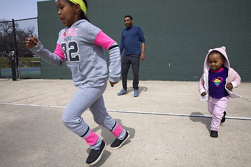 Aragaw Beyene, center, of Washington, plays with his cousins' children, Eldana Tilahune, 6, left, and Meklit Tilahune, 2, Monday, March 16, 2020, at a public park in northwest Washington. Beyene and his extended family are taking turns watching each other's children so the others can work while schools are closed due to coronavirus precautions. &quot;I normally drive an Uber,&quot; says Beyene, &quot;but it's scary to drive an Uber right now with the coronavirus. I haven't gone to work since Friday. Although I hear there is not much work.&quot; The family says they may stop taking the children to parks outside due to coronavirus fears. (AP Photo/Jacquelyn Martin)