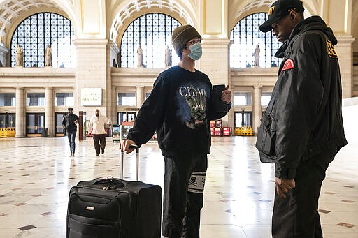 A traveler talks with a security officer at Washington Union Station, a major transportation hub in the nation's capital, Monday, March 16, 2020. The train station was nearly empty during morning rush hour as many government and private sector workers stay home during the coronavirus outbreak. (AP Photo/J. Scott Applewhite)