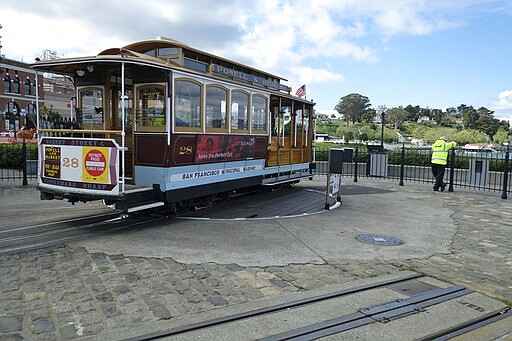 A cable car operator looks out toward the Golden Gate Bridge while standing at the near-empty Hyde Street turnaround Monday, March 16, 2020, in San Francisco. Officials in six San Francisco Bay Area counties issued a shelter-in-place mandate Monday affecting nearly 7 million people, including the city of San Francisco itself. The order says residents must stay inside and venture out only for necessities for three weeks starting Tuesday in a desperate attempt by officials to curb the spread of the novel coronavirus. (AP Photo/Eric Risberg)