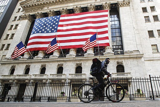 A delivery worker rides his electric bicycle past the New York Stock Exchange, Monday, March 16, 2020, in New York. New York leaders took a series of unprecedented steps Sunday to slow the spread of the coronavirus, including canceling schools and extinguishing most nightlife in New York City. (AP Photo/John Minchillo)