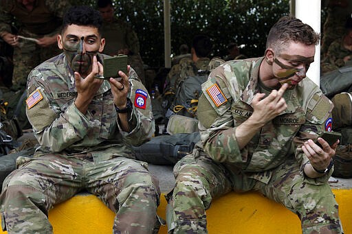 In this Jan. 26, 2020, photo, two American paratroopers with the 82nd Airborne Division apply camouflage face paint before jumping into Melgar, Colombia. This will likely be the only time most of these paratroopers will jump into a foreign country. (AP Photo/Sarah Blake Morgan)