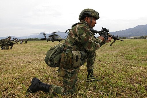 In this Jan. 24, 2020, photo, a Colombian Lancero paratrooper kneels at the ready during training with their American counterparts, in Melgar, Colombia. The country has a highly skilled airborne division. (AP Photo/Sarah Blake Morgan)