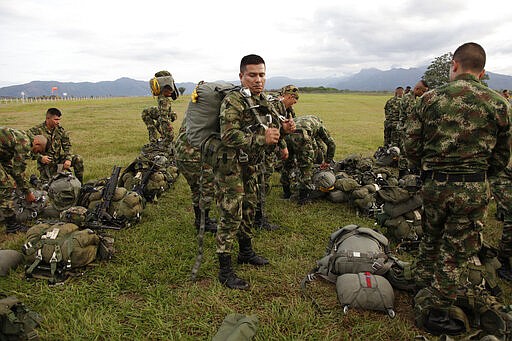 In this Jan. 26, 2020, photo, a Colombian paratrooper works to secure his parachute pack before a training exercise at Tolemaida Air Base, in Colombia. The gear soldiers jump with can weigh nearly 100 pounds. (AP Photo/Sarah Blake Morgan)