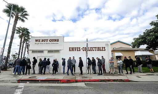 People wait in a line to enter a gun store in Culver City, Calif., Sunday, March 15, 2020. Coronavirus concerns have led to consumer panic buying of grocery staples, and now gun stores are seeing a similar run on weapons and ammunition as panic intensifies. (AP Photo/Ringo H.W. Chiu)