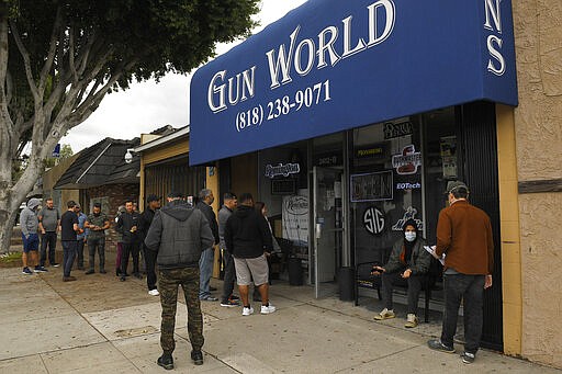 Gun store patrons wait in line, Sunday, March 15, 2020, in Burbank, Calif. Consumers are buying all kinds of goods in large quantities amid coronavirus concerns, putting pressure on inventories. Some people in line simply wanted to stock up on ammunition, while others said they were preparing in case their homes get invaded for food and other necessities. (AP Photo/Mark J. Terrill)