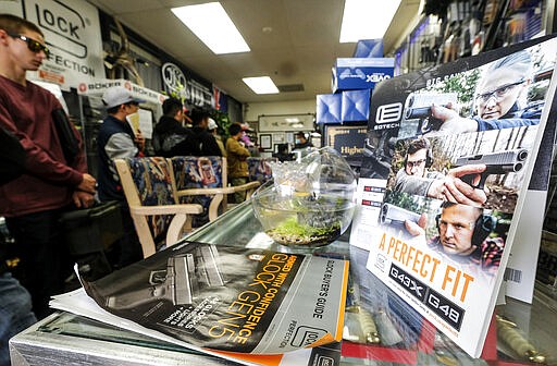 People wait in a line at a gun at store amid merchandise displays, in Arcadia, Calif., Sunday, March 15, 2020. Coronavirus concerns have led to consumer panic buying of grocery staples and now gun stores are seeing a run on weapons and ammunition as panic intensifies. (AP Photo/Ringo H.W. Chiu)