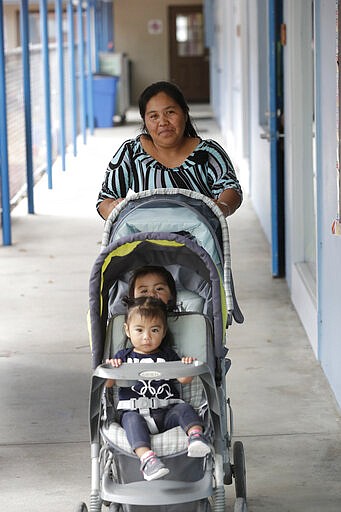 In this, Wednesday, Feb. 12, 2020 photo, Maria Juarez, a Guatemalan mother of three from San Marcos who works picking tomatoes, picks up one of her children and the child of another worker at the Redlands Christian Migrant Association's Rollason Child Development Center in Immokalee, Fla.   Small, poor and largely Latino communities around the U.S. historically have been undercounted, an analysis by The Associated Press shows, posing challenges for Census workers in a tally that's supposed to ensure federal dollars get to communities needing them most. (AP Photo/Wilfredo Lee)