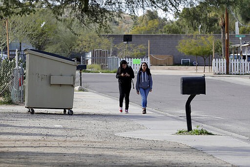 Children walk along a side street Friday, Jan. 24, 2020 in Guadalupe, Ariz. Founded by Yaqui Indian refugees from Mexico more than a century ago, Guadalupe is named for Mexico's patron saint, Our Lady of Guadalupe, and is fiercely proud of its history. The town known for sacred Easter rituals featuring deer-antlered dancers also is wary of outsiders as it prepares for the 2020 census. (AP Photo/Matt York)