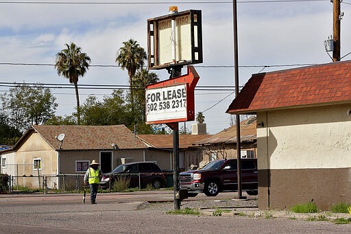 A worker stands outside an empty building Friday, Jan. 24, 2020 in Guadalupe, Ariz. Founded by Yaqui Indian refugees from Mexico more than a century ago, Guadalupe is named for Mexico's patron saint, Our Lady of Guadalupe, and is fiercely proud of its history. The town known for sacred Easter rituals featuring deer-antlered dancers also is wary of outsiders as it prepares for the 2020 census. (AP Photo/Matt York)