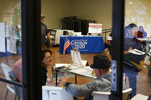 In this Feb. 8, 2020, photo, people volunteer to get people registered to vote and a booth offering employment for the upcoming 2020 census stands in the background, during the celebration of the town's 45th year since it was incorporated, in Guadalupe, Ariz. Today, nearly a third of Guadalupe's 6,500 residents say they are Native American and about 75% of all races identify as Hispanic. A third also struggle with poverty in a community where the median annual household income is around $32,000 and the average owner-occupied home is valued at less than $90,000. (AP Photo/Dario Lopez-MIlls)