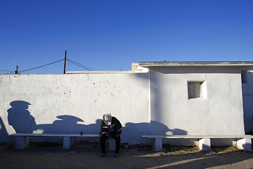 In this Feb. 8, 2020, photo, men gather outside of the Our Lady of Guadalupe church in the town of Guadalupe, Ariz., near Phoenix. Founded by Yaqui Indian refugees from south of the border more than a century ago, the town named for Mexico's patron saint, is proud of its history but wary of outsiders as it prepares for the 2020 Census count its leaders hope will help better fund a $12 million budget to fill potholes and mend aging sewage lines. (AP Photo/Dario Lopez-MIlls)