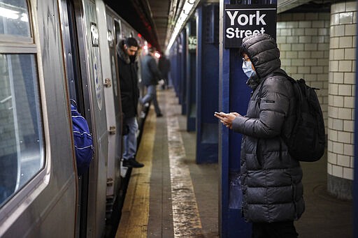 A subway customer wearing a face mask waits to board a car in the Brooklyn borough of New York, Monday, March 16, 2020. New York leaders took a series of unprecedented steps Sunday to slow the spread of the coronavirus, including canceling schools and extinguishing most nightlife in New York City.  According to the World  Health Organization, most people recover in about two to six weeks, depending on the severity of the illness.  (AP Photo/John Minchillo)