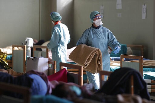 Patients lie on beds at one of the emergency structures that were set up to ease procedures at the Brescia hospital, Italy, Monday, March 16, 2020. For most people, the new coronavirus causes only mild or moderate symptoms. For some, it can cause more severe illness, especially in older adults and people with existing health problems. (AP Photo/Luca Bruno)