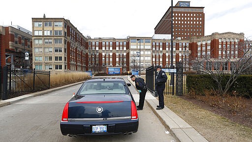 Security guards screen visitors before entering Henry Ford Hospital in Detroit, Monday, March 16, 2020. U.S. hospitals are setting up triage tents, calling doctors out of retirement, guarding their supplies of face masks and making plans to cancel elective surgery as they brace for an expected onslaught of coronavirus patients. (AP Photo/Paul Sancya)