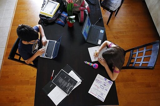 Tony Berastegui, left, and his sister Giselle, age 12 and nine respectively, do their school work at home on the dining room table as the COVID-19 coronavirus pandemic forced schools to close Monday, March 16, 2020, in Laveen, Ariz. (AP Photo/Ross D. Franklin)