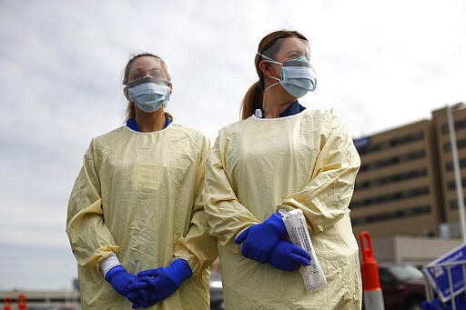 Physicians Assistant Jessica Hamilton, left, and Amena Beslic RN holds a swab and test tube kit to test people for COVID-19 at a drive through station set up in the parking lot of the Beaumont Hospital in Royal Oak, Mich., Monday, March 16, 2020. (AP Photo/Paul Sancya)