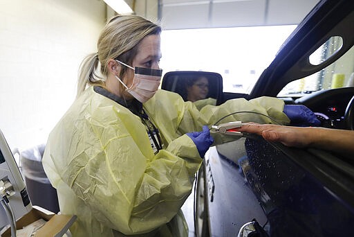 Courtney Crabtree check the temperature of a customer at a Witham Health Services drive-through Community Viral Screening center, Monday, March 16, 2020, in Whitestown, Ind. The screening center for coronavirus will help provide guidance and reduce unnecessary trips to the emergency room. (AP Photo/Darron Cummings)