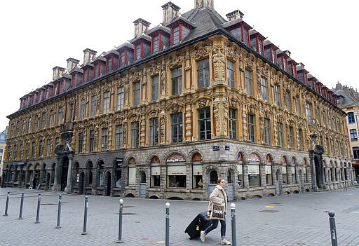 A woman walks through the main square in Lille, northern France, Monday, March 16, 2020. France's government announced Saturday closing restaurants, bars and other establishments to limit the spread of the new coronavirus. For most people, the new coronavirus causes only mild or moderate symptoms, such as fever and cough. For some, especially older adults and people with existing health problems, it can cause more severe illness, including pneumonia. (AP Photo/Michel Spingler)