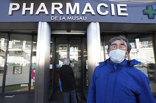 A man wearing a mask leaves a drugstore Monday March 16, 2020 in Strasbourg, eastern France. For most people, the new coronavirus causes only mild or moderate symptoms. For some it can cause more severe illness. (AP Photo/Jean-Francois Badias)